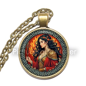 May include: A round pendant necklace with a bronze chain. The pendant features a woman in a red and gold outfit, holding a staff, with a fiery background. The pendant is framed by a Greek key design.