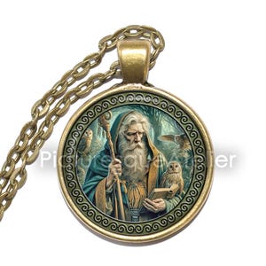 Op de afbeelding: Een ronde gouden ketting met een glazen cameo met daarop een bebaarde man in een groene mantel die een staf en een boek vasthoudt. Twee uilen zitten op takken achter hem. De cameo is omgeven door een decoratieve gouden rand.