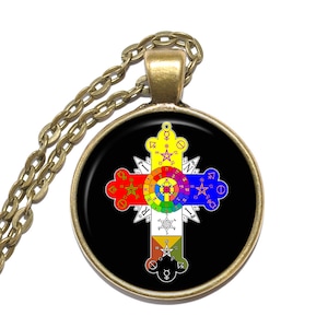 May include: A gold chain necklace with a round pendant featuring a black background and a white cross with a colorful circle in the center. The cross is surrounded by symbols and numbers.