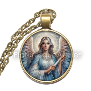 May include: A round pendant necklace with a detailed illustration of an angel. The angel has blue eyes, long silver hair, and white wings. The pendant is gold-colored and hangs from a matching chain. The text "Picturesque Atelier" is visible.