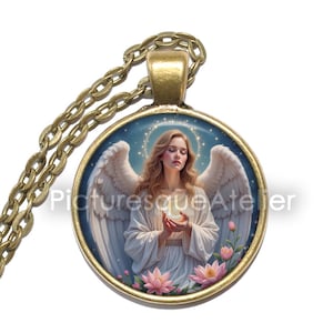 Pu&ograve; includere: Una collana con pendente rotondo con una catena color oro. Il pendente presenta un'illustrazione di un angelo con ali bianche, che tiene in mano un globo luminoso. Fiori rosa sul fondo del pendente. Il testo "Picturesque Atelier" &egrave; sul pendente.