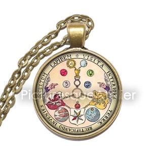 Peut inclure: Un collier en or avec un pendentif rond représentant une illustration vintage d'un diagramme circulaire avec des symboles et du texte. Le texte sur le pendentif est "Visita Interiora Terrae Rectificando Invenies Occultum Lapidem".