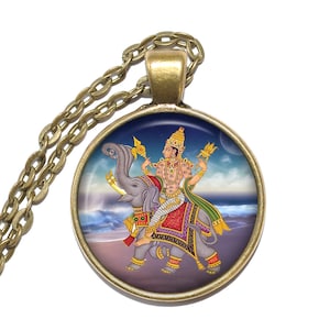 May include: A round pendant necklace with a detailed illustration of a deity riding an elephant. The pendant has a gold-colored frame and chain. The illustration features vibrant colors and intricate details, set against a backdrop of a beach and sky.
