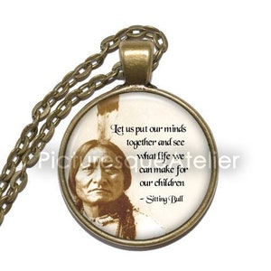 May include: A bronze necklace with a glass pendant featuring a black and white portrait of Sitting Bull. The pendant has a quote from Sitting Bull: "Let us put our minds together and see what life we can make for our children - Sitting Bull".
