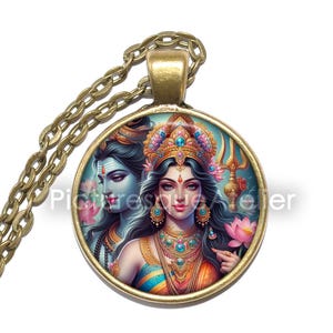 May include: A gold necklace with a round pendant featuring a colorful illustration of Shiva and Parvati, Hindu deities, against a blue background.