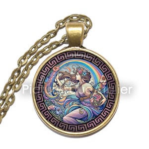 May include: A gold chain necklace with a round pendant featuring a colourful illustration of a woman with flowers in her hair and a rainbow behind her. The pendant is surrounded by a gold Greek key border.