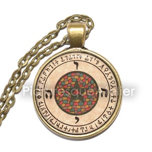 Può includere: Una collana con catena dorata con un ciondolo rotondo che presenta un design a forma di stella con un motivo a mosaico in tonalità di rosso, verde, blu e giallo. Il ciondolo è circondato da un cerchio di testo ebraico.