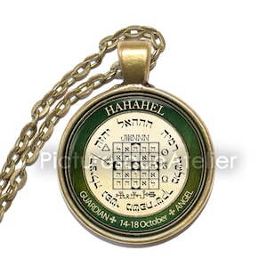 Könnte beinhalten: Eine goldene Halskette mit einem runden Anhänger in Grün und Gold. Der Anhänger zeigt eine hebräische Inschrift und ein quadratisches Gitter mit hebräischen Buchstaben. Der Text auf dem Anhänger lautet "HAHAHEL GUARDIAN * 14-18 October * ANGEL".