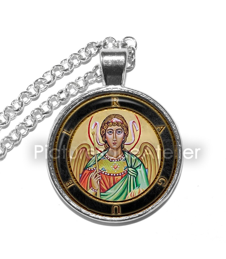 May include: A silver chain necklace with a round pendant featuring a colorful icon of an angel with wings and a halo. The pendant has a black background with gold lettering around the edge.