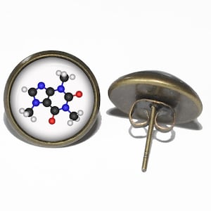Op de afbeelding: Een paar bronzen oorbel studs met een witte achtergrond en een kleurrijke chemische structuur. De chemische structuur is een weergave van cafeïne.