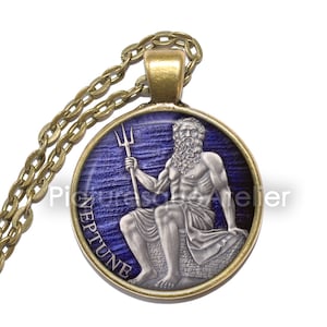 May include: A round pendant necklace with a gold chain. The pendant features a blue and silver image of Neptune, the Roman god of the sea, holding a trident. The pendant is inscribed with the word "Neptune".