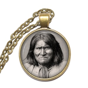 Puede incluir: Un collar de cadena dorada con un colgante redondo que presenta un retrato en blanco y negro de una mujer nativa americana.