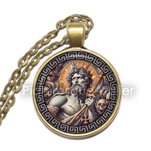 May include: A gold necklace with a round pendant featuring a detailed illustration of a bearded man with a trident, surrounded by skulls and a Greek key border.