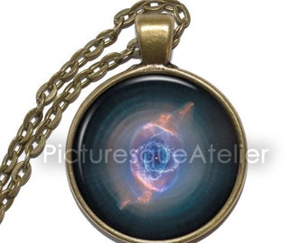 May include: A bronze necklace with a round glass pendant featuring a colorful nebula image. The pendant is surrounded by a bronze frame.