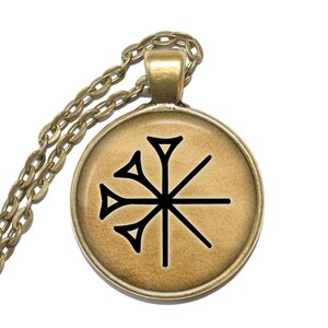 May include: A gold chain necklace with a round pendant featuring a black symbol on a beige background.