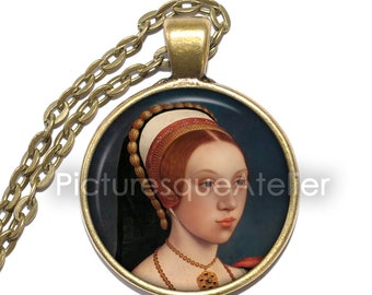 May include: A gold chain necklace with a round pendant featuring a portrait of a woman with red hair wearing a white and gold headdress. The portrait is set against a dark blue background.