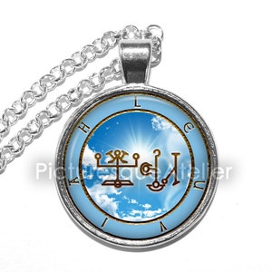 Puede incluir: Collar de plata con un colgante redondo que presenta un cielo azul con nubes blancas y un sello dorado. El sello est&aacute; rodeado por un c&iacute;rculo con las letras "L A H I U C E" en dorado.
