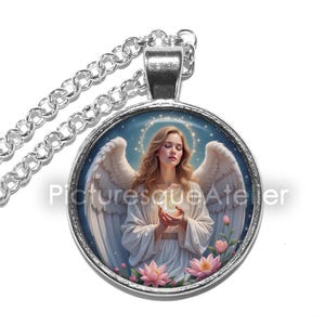 Pu&ograve; includere: Collana con pendente argentato con un ciondolo rotondo raffigurante un angelo. L'angelo ha i capelli biondi, ali bianche e tiene in mano un globo luminoso. Il ciondolo &egrave; circondato da una cornice argentata e da una catena sottile. Testo: "Picturesque Atelier".