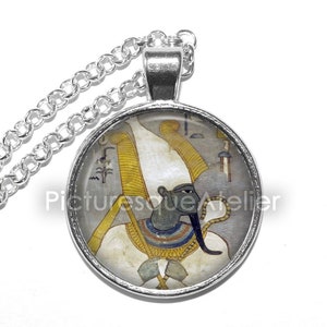 May include: Silver necklace with a round glass pendant featuring a colorful image of an Egyptian god with a white headdress and a blue face.