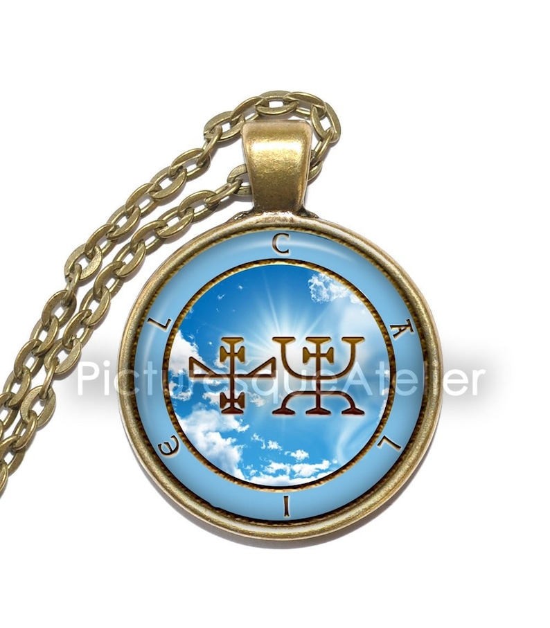 May include: A gold pendant necklace with a round glass charm featuring a blue sky with white clouds and a gold sigil. The sigil is surrounded by a gold circle with the letters "L.I.E.G.I.A.L" inscribed around it.