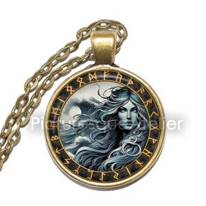 May include: A round pendant necklace with a bronze chain. The pendant features a woman with long blue hair and blue eyes, set against a stormy sea. The pendant is framed by a black border with gold-colored runes.