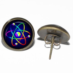 Peut inclure: Une paire de boucles d'oreilles clous en bronze avec un motif d'atome arc-en-ciel sur le devant. L'atome est sur un fond bleu foncé.