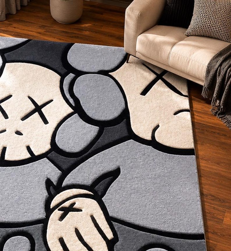 Puede incluir: Una alfombra rectangular con un patr&oacute;n gr&aacute;fico repetitivo de personajes de dibujos animados estilizados con ojos en forma de X. El dise&ntilde;o utiliza una paleta de colores crema, gris claro y gris oscuro, con contornos negros gruesos.