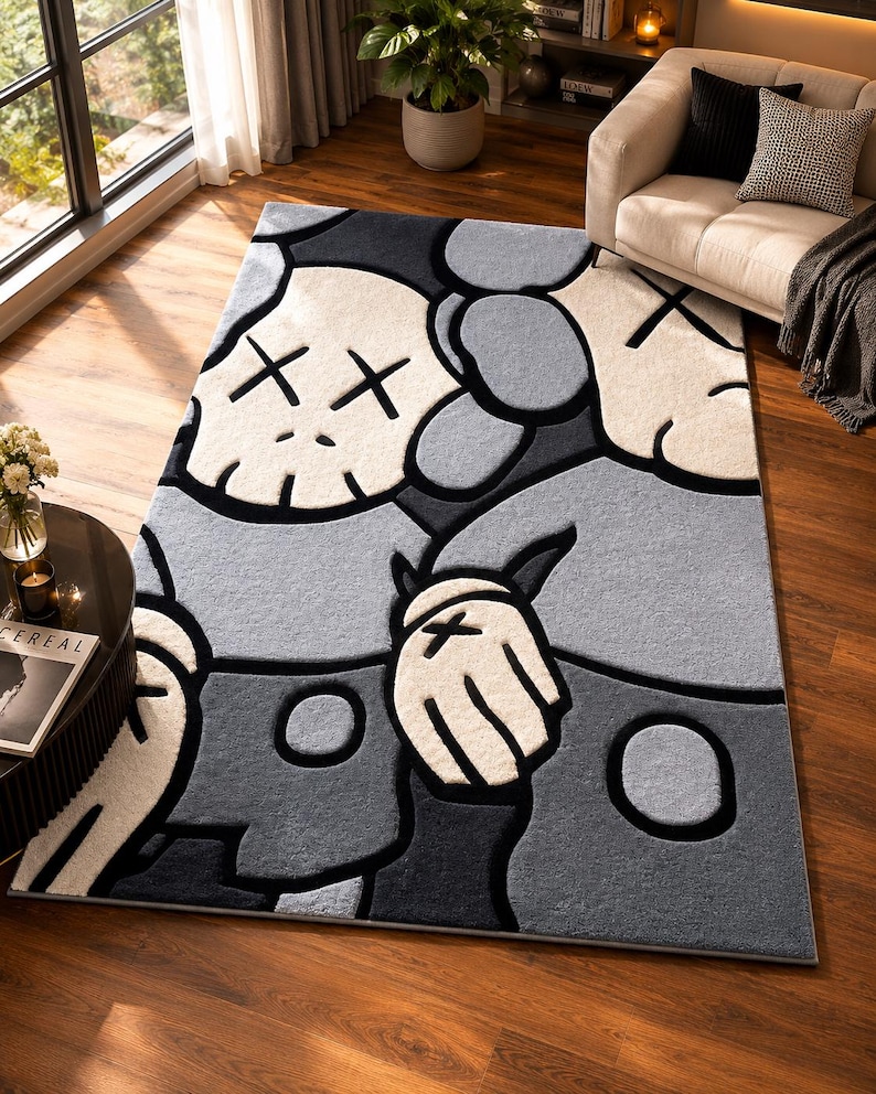 Puede incluir: Una alfombra rectangular que presenta un patr&oacute;n gr&aacute;fico repetitivo de personajes de dibujos animados estilizados con ojos en forma de X. El dise&ntilde;o utiliza una paleta de colores monocrom&aacute;tica de negro, gris oscuro, gris claro y blanco roto.