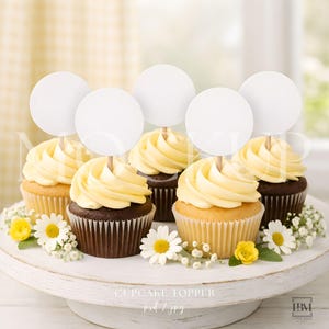 May include: Six cupcakes with yellow frosting and white circular toppers on wooden sticks are arranged on a white cake stand. The cupcakes are decorated with daisies and small yellow flowers. The text "CUPCAKE TOPPER" is visible.