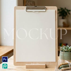 May include: A wooden clipboard with a silver clip holding a blank white paper. The word "MOCKUP" is printed in large, light letters across the paper. A small wooden stand supports the clipboard. The image includes a small succulent in a green pot and a bundle of crayons.