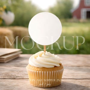 Może przedstawiać: Babeczka z białym lukrem i okrągłym białym topperem na drewnianym patyczku. Babeczka stoi na drewnianej powierzchni. Tekst "CUPCAKE TOPPER 2X2 psd / jpg" znajduje się na dole.