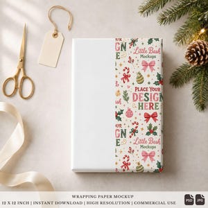 May include: A rectangular gift box wrapped in white paper with a vertical band featuring a festive Christmas pattern of bows, candy canes, ornaments, and holly. The text reads Little Bash Mockups and Place Your Design Here.