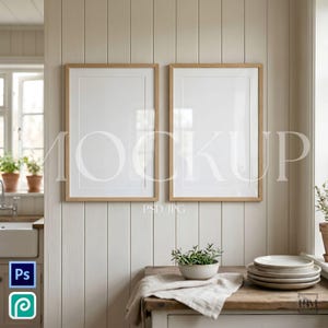 Op de afbeelding: Twee ingelijste kunst-mockups met licht houten frames hangen aan een neutraal getinte muur. Daaronder toont een houten tafel een stapel borden, een kleine kom met groen en een linnen doek. Het woord "MOCKUP" is zichtbaar op de frames.