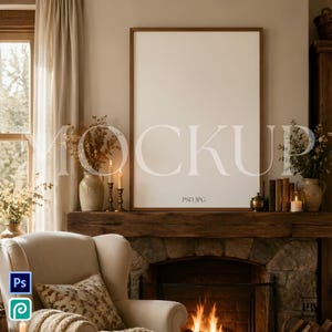 May include: A cozy living room scene with a fireplace, armchair, and a framed mockup. The fireplace has a stone facade and a wooden mantel. A lit fire is visible. The mockup is a large, blank canvas with a wooden frame. The room is decorated in neutral tones.
