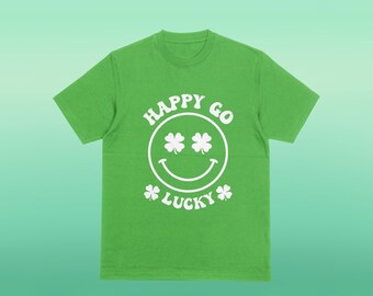 以下が含まれることがあります： 明るい緑色のTシャツに白いグラフィック。グラフィックは、クローバーの目のスマイリーフェイスと「HAPPY GO LUCKY」という言葉を円形デザインで特徴としています。シャツは柔らかい素材で作られています。