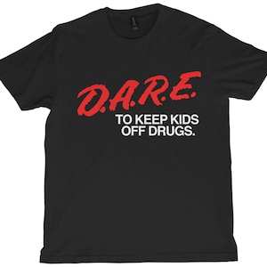 May include: Black t-shirt with the red text "D.A.R.E. TO KEEP KIDS OFF DRUGS." The text is in a bold, stylized font. The shirt is a crew neck style.