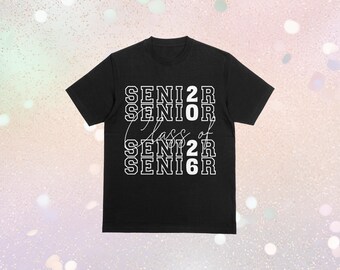 以下が含まれることがあります： 白文字で「SENIOR 2026」と重ねてデザインされた黒いTシャツ。「Class of」の文字は筆記体です。Tシャツはクルーネックです。