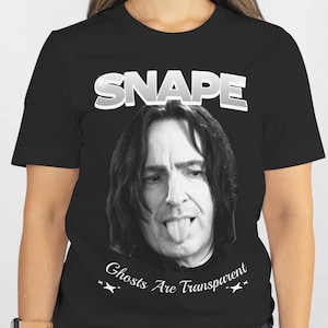 May include: Black t-shirt featuring a grayscale image of a man with his tongue out, with the word "SNAPE" above the image and the text "Ghosts Are Transparent" below. The shirt is a crew neck.