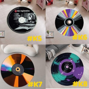 Pode incluir: Quatro tapetes redondos com design de CD ou disco de vinil. Um tapete apresenta uma imagem a preto e branco com o texto "late registration" e um urso. Outros tapetes t&ecirc;m designs coloridos em preto, roxo, amarelo e verde-azulado.