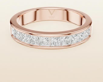 May include: Rose gold band ring with a channel setting of square-cut, clear gemstones. The ring has a polished finish and a minimalist design, suitable for everyday wear or special occasions. The ring is a piece of jewelry.