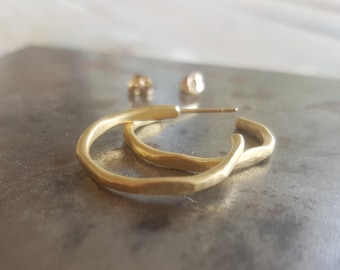 May include: A pair of gold hoop earrings with a hammered texture. The earrings are simple and elegant, and would make a great gift.