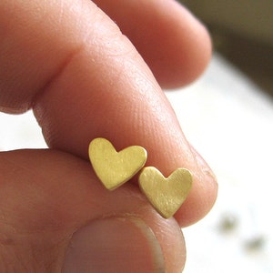 May include: A pair of gold heart-shaped stud earrings.
