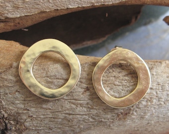 May include: A pair of gold-toned hammered metal earrings with a circle design. The earrings are simple and elegant.