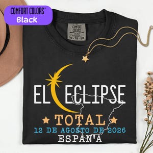 May include: A black t-shirt featuring a graphic design with a yellow crescent moon and star, a white outline of Spain, and the text EL ECLIPSE TOTAL 12 DE AGOSTO DE 2026 ESPAÑA. The shirt has a Comfort Colors brand label on the inside neck area.