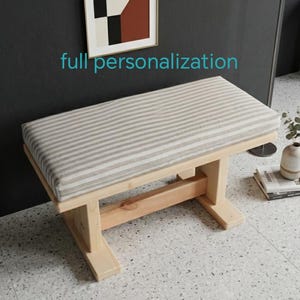 May include: A white ceramic mug with a black handle and the text "But First, Coffee" in a bold, black font. The mug is filled with a dark liquid, likely coffee, and rests on a light-coloured surface.