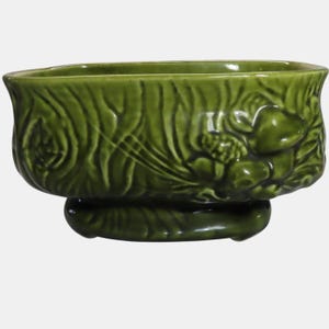 May include: A white ceramic mug with a black handle and the text "But First, Coffee" in a black, bold font. The mug is on a white surface.