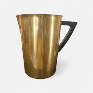 May include: A tall, gold-colored pitcher with a black, triangular handle. The pitcher has a smooth, reflective surface and a slightly flared top. The handle is attached to the side of the pitcher, providing a secure grip. The pitcher is likely made of metal.