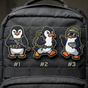 May include: Three embroidered penguin patches with military-themed designs. One penguin holds a rifle, another carries a backpack, and the third wears goggles and a hat while holding a fish. Each patch is numbered.