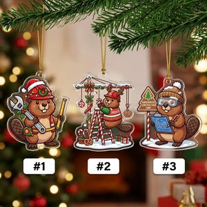 May include: Three clear acrylic Christmas ornaments featuring cartoon beavers. Ornament 1 shows a beaver with a wrench and ruler. Ornament 2 shows a beaver on a ladder building a structure. Ornament 3 shows a beaver with a blueprint and sign.