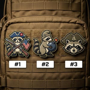 May include: Three embroidered patches featuring raccoon designs. One raccoon wears a tricorn hat and holds crossed rifles and a flag. Another holds a bomb, and the third wears a pirate hat. Each patch has a number label.